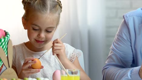 Father-and-daughter-preparing-for-Easter,-drawing-eggs-with-colorful-paints