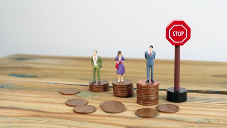 Miniature-people-standing-on-piles-of-coins