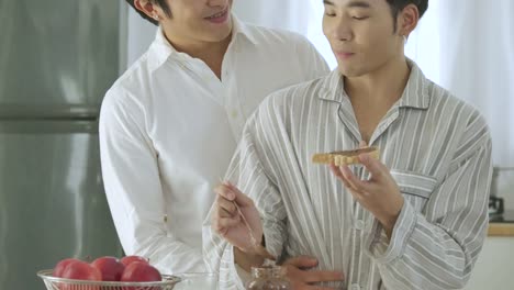 Attractive-young-asian-gay-couple-having-breakfast-in-kitchen.-Man-cooking-breakfast-for-him-boyfriend-with-attractive-smiling.-People-with-gay,-homosexual,-relationship-concept.