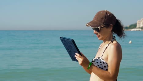 Woman-typing-on-tablet-on-background-of-sea.