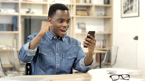 Excited-African-Man-Enjoying-Success-while-Using-Smartphone