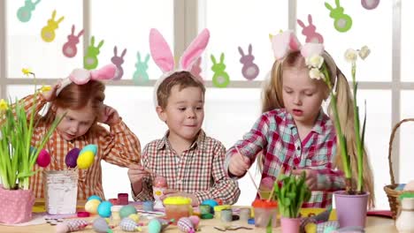 Happy-children-wearing-bunny-ears-painting-eggs-on-Easter-day.-Little-girls-preparing-for-the-Easter.