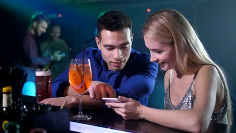 Dating-couple-using-phone-sitting-at-bar-counter