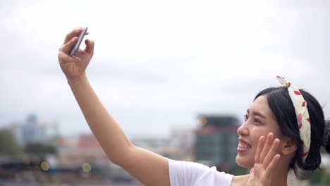 Hermosa-joven-asiática-que-tiene-video-chat-mostrando-ver-y-compartir-con-amigos-en-las-redes-sociales-vacaciones-de-verano.