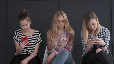 Three-girls-chatting-using-their-mobile-phones