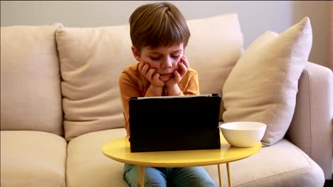 Niño-usando-Tablet-PC-en-la-cama-en-casa.-Niño-lindo-en-el-sofá-está-viendo-dibujos-animados,-jugando-juegos-y-aprendiendo-desde-el-ordenador-portátil.-Educación,-diversión,-ocio,-felicidad,-tecnología-informática-moderna-y-comunicación.