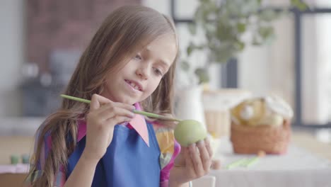 Portrait-of-cute-girl-painting-Easter-egg.