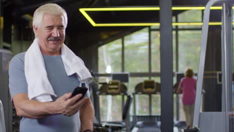 Viejo-hombre-usando-el-teléfono-en-el-gimnasio