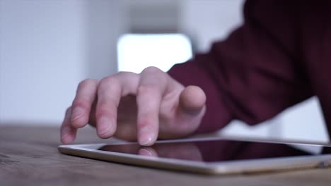 Close-up:-the-use-of-the-tablet.-A-man-at-a-business-meeting-uses-a-Tablet.-Modern-technologies.-Unknown-man-holding-a-finger-on-the-touch-screen-of-the-tablet.