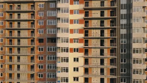 Aerial-view-of-the-facade-of-a-residential-apartment-building-under-construction.-High-rise-building-with-windows-and-balconies.-Construction-industry.-Urbanization