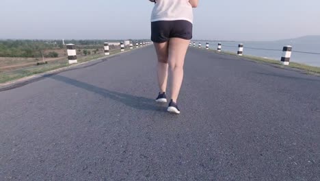 Asian-women-jogging-in-the-street-in-the-early-morning-sunlight-at-water-storage-Pa-Sak-Jolasid-Dam.-concept-of-losing-weight-with-exercise-for-health.-Slow-motion,-Bottom-view