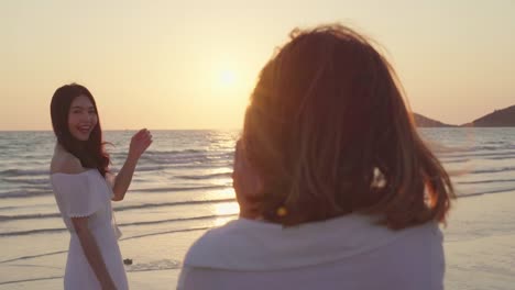 Junges-asiatisches-lesbisches-Paar,-das-sich-in-der-Nähe-des-Strandes-fotografiert.-Schöne-Frauen-lgbt-Paar-glücklichen-romantischen-Moment,-wenn-Sonnenuntergang-am-Abend.-Lifestyle-lesbisches-Ehepaar-reist-nach-Strandkonzept