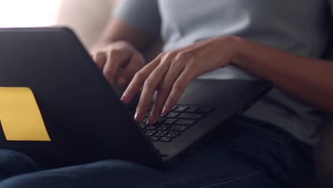 Slow-Motion-:-Close-up-hands-typing-using-laptop-computer-sharing-online-working-blogger-influencer,-Asian-female-browsing-social-media-communication-while-sitting-on-the-sofa-in-the-living-room-at-home.