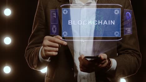 Businessman-shows-hologram-with-text-Blockchain