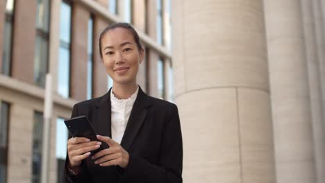 Asiatische-Geschäftsfrau-mit-Telefon-draußen