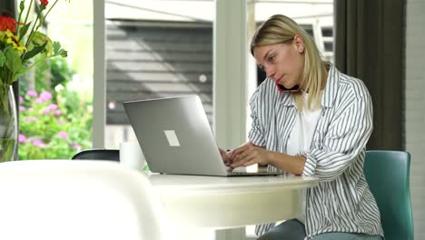 Serious-caucasian-female-freelancer-working-remotely-at-home-interior-using-laptop-computer