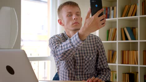 Caucasian-businessman-sitting-in-front-of-laptop-searching-for-network-on-bookshelves-background.