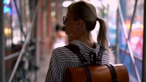 Back-view-of-female-traveller-with-stylish-touristic-backpack-calling-to-friend-for-talking