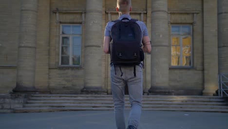 A-back-viev-of-a-young-photographer-who-is-approaching-an-old-church-with-an-expensive-digital-camera