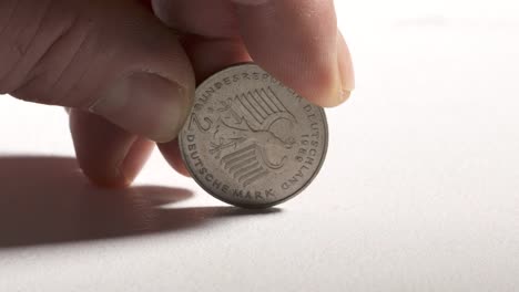 2-Deutsche-Mark-coin-spinning-and-dropping-on-desk