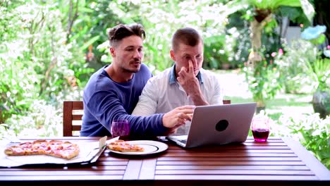 Gay-couple-having-pizza-for-lunch.-Pointing-at-screen.