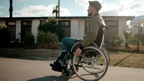 Young-man-with-paralyzed-legs-in-wheelchair-is-walking-alone-in-city-streets