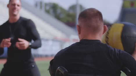 Wheelchaired-athlete-and-trainer-throwing-medicine-ball