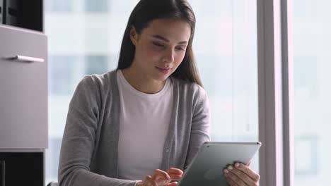 Joven-empresaria-enfocada-sosteniendo-usando-tableta-digital-en-la-oficina