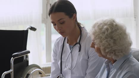 Young-woman-doctor-consult-disabled-handicapped-old-grandma-patient