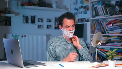 office-worker-shaves-and-works-on-a-laptop-at-the-same-time