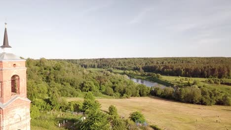 Aerial-view-of-the-Russian-forest,-river-and-steppe-overlooking-an-abandoned-Church-and-architectural-objects