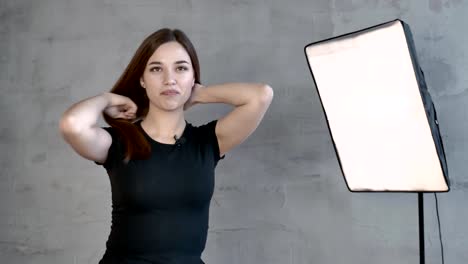 Caucasian-girl-in-front-of-a-gray-wall-laughs,-waving-her-hair