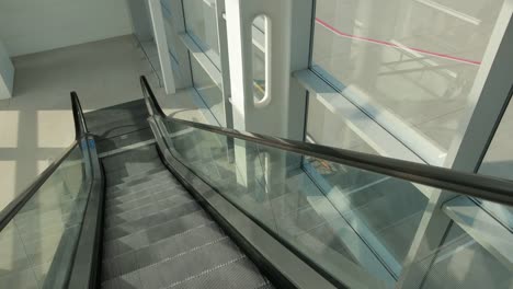 Escalator-in-airport-is-running-down-to-way-that-leads-airfield,-runway.