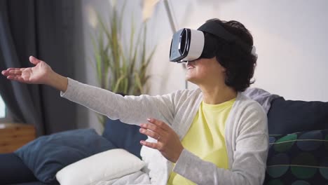 Smiling-happy-woman-is-sitting-on-sofa-and-using-modern-digital-technology