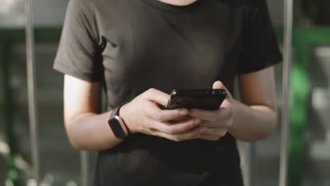 Beautiful-teenage-asian-girl-athlete-running-using-smartphone-sharing-messages-on-social-media-communication-while-standing-beside-on-the-street-urban.