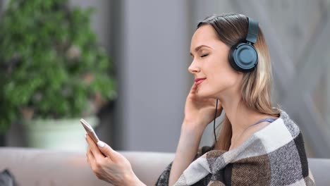 Chica-sonriente-escuchando-música-en-auriculares-utilizan-el-teléfono-inteligente.-Disparo-de-cierre-medio-en-cámara-RED-de-4k