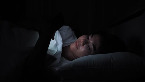 Close-up-Asian-woman-Using-smartphone-on-the-bed-in-home-at-night