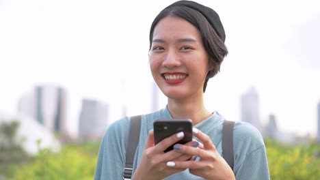 Close-up-face-of-asian-woman-using-smart-phone.-Happy-female-face-with-white-teeth-pretty-face-posing-for-close-up-portrait-outdoor.