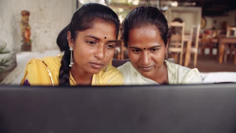 Two-women-chilling-sipping-drinks-using-technology-in-cafe