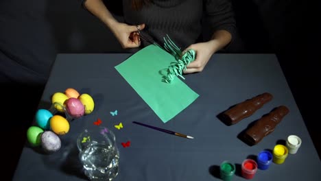 Hands-cut-and-curl-the-fringe-of-the-green-paper-with-scissors-over-easter-table