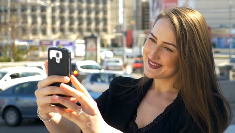 Business-woman-taking-selfies-with-smartphone-camera-with-city-traffic-street-in-background