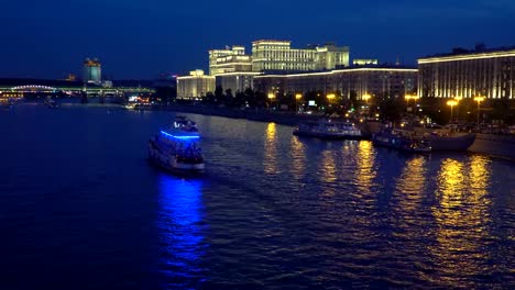 Nachtverkehr-von-Sportbooten-auf-einem-Fluss,-Stadt