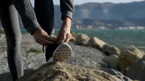 Sports-woman-getting-ready-for-run-tying-laces-of-running-shoes-on-the-beach