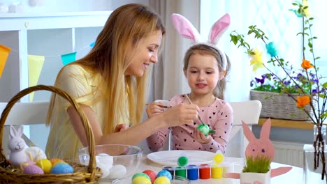 ¡Feliz-Pascua-de-resurrección!-Madre-y-su-pequeña-hija-con-divertidas-orejas-de-conejo-para-colorear-huevos-de-Pascua