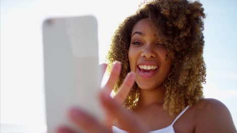 Voluptuosa-mujer-étnica-utilizando-teléfonos-inteligentes-en-la-playa