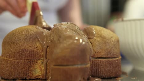 pastry-chef--hands-glazed-Easter-sweet-bread-cakes-with-chocolate,-closeup-on-the-worktop-in-confectionery