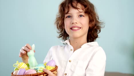 Un-niño-tiene-un-conejito-de-Pascua-y-un-conjunto-de-huevos-de-Pascua-decorativos.-El-muchacho-se-ríe-alegremente.-Cámara-lenta