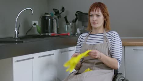 Mujer-alegre-en-silla-de-ruedas-haciendo-las-tareas-domésticas