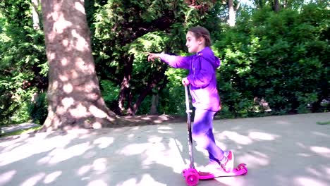 Little-child-learning-to-ride-a-scooter-in-a-city-park