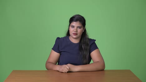 Young-overweight-beautiful-Indian-businesswoman-against-green-background